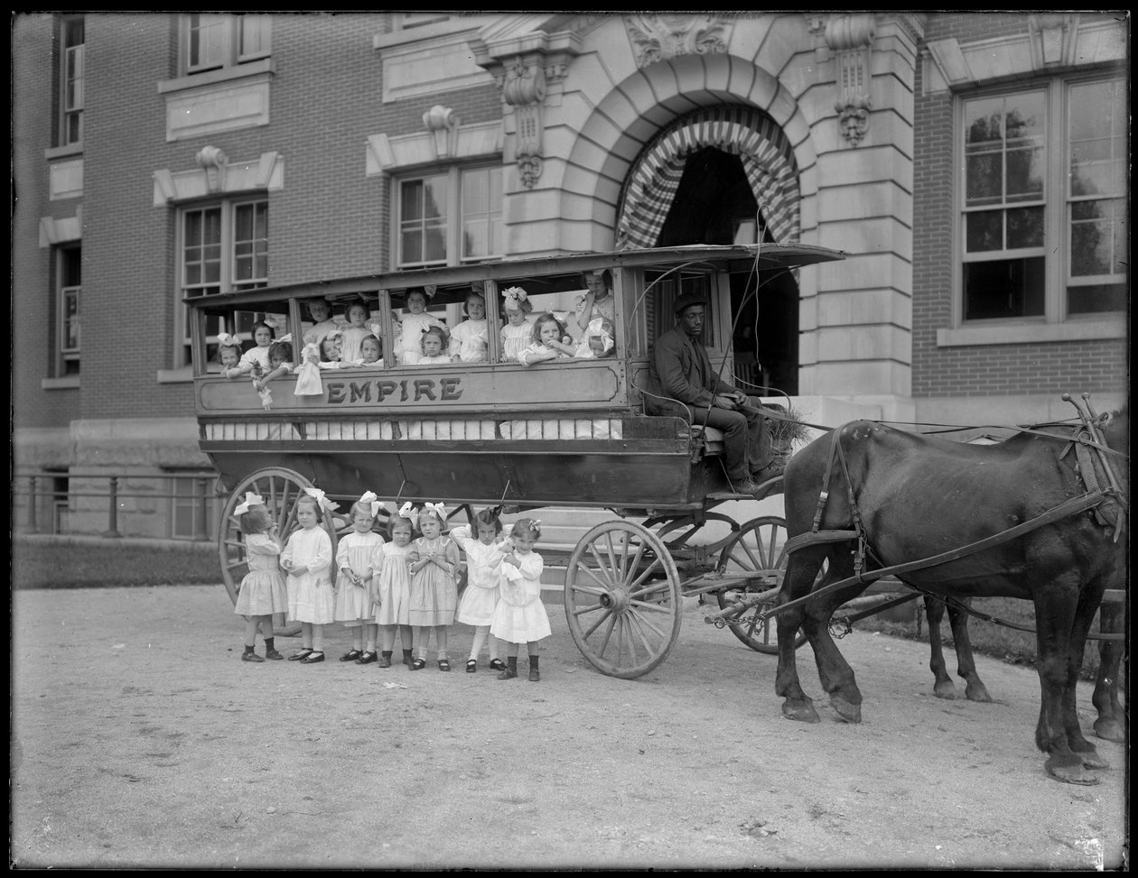 Małe dziewczynki pozują przed i przed wozem konnym, przed niezidentyfikowanym budynkiem, prawdopodobnie rzymskokatolickim azylem dla sierot, Kingsbridge, Bronx, ok. 1910 autorstwa William Davis Hassler