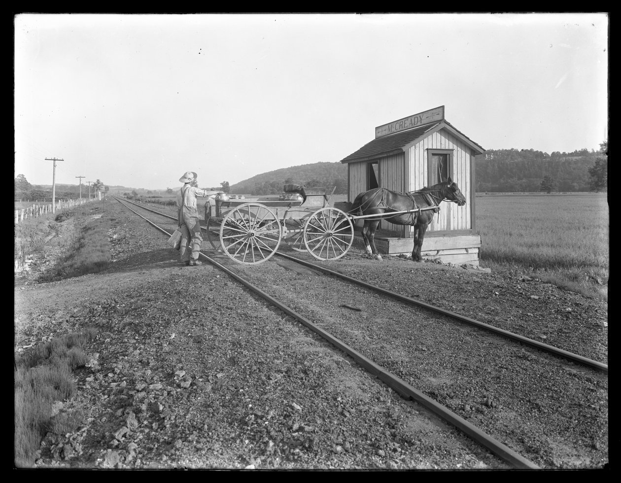 Niezidentyfikowany mężczyzna ładujący mleko na wóz konny zaparkowany nad torami kolejowymi przed farmą McCready, Pensylwania, ok. 1913 autorstwa William Davis Hassler