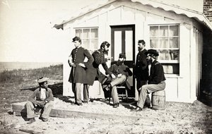 Pięciu żołnierzy z wojny secesyjnej zebrało się na brudnej werandzie przed domem, afroamerykańska młodzież siedziała obok nich, 1861-65 autorstwa American Photographer