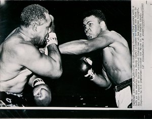 Młody Cassius Clay strzela lewą stroną przeciwko weteranowi Archie Moore w pierwszej rundzie walki w Los Angeles autorstwa American Photographer