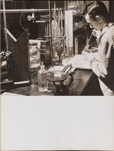 [Mężczyzna w laboratorium używa obu rąk do umieszczenia dużej pipety w zlewce]. autorstwa Arnold Eagle