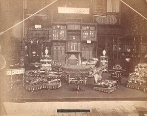 Wystawa S. Howard & Sons -- Gmach Główny, Kolekcja mebli, w tym krzesła tapicerowane, stoły, kominek, szafy i regały. Na ścianach dywany, a na stołach i półkach wazony