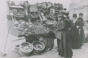 Przy jego straganie stoi sklep spożywczy, który obsługuje kobietę autorstwa English Photographer