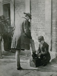 Młody pucybut lśniący męskie buty na ulicy autorstwa English Photographer