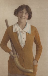 Ładna dziewczyna, w swetrze z dzianiny, z perłowymi kolczykami, trzymająca kij hokejowy (zdjęcie) autorstwa English Photographer
