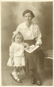 Ładna dziewczyna, mama lub guwernantka, pokazująca zdjęcia małemu dziecku (zdjęcie czarno-białe) autorstwa English Photographer
