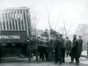 Tłum gapiów stoi, gdy nosorożec jest rozładowywany z ciężarówki przez opiekunów w londyńskim zoo w 1924 roku autorstwa Frederick William Bond