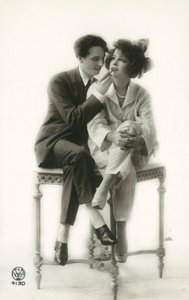 Androgyniczny mężczyzna w garniturze nakłada szminkę na usta dziewczyny w piżamie autorstwa French Photographer