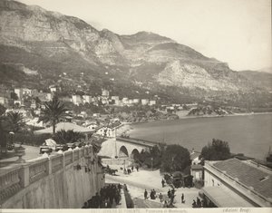 Panoramiczny widok na Montecarlo w Monako. Scena przedstawia różnych przechodniów; po lewej stronie w zbliżeniu marmurowa balustrada autorstwa Giacomo Brogi