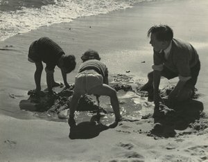 Trójka dzieci bawiących się piaskiem na plaży.