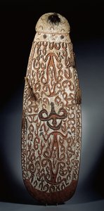 Owalna tarcza Asmat, wyrzeźbiona w reliefie z przewijanym ornamentem zawierającym wysoce stylizowane postacie, plecione frędzle do brzegu (drewno, rafia i pióra) autorstwa Guinean New