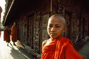 Młody początkujący mnich przed rzeźbionymi panelami z drewna tekowego. Klasztor Shwenandaw, Mandalay, Birma. autorstwa James L Stanfield