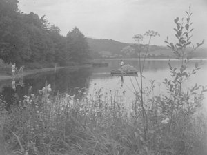 Mężczyzna łowiący ryby w łodzi na Estwaite Water i dwie dziewczynki na brzegu wody