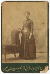 Fotografia kobiety stojącej przy krześle i trzymającej książkę, koniec XIX wieku. autorstwa Louis Janousek