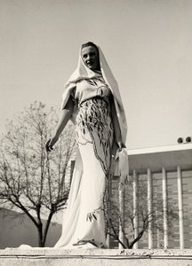 Model w wieczorowej sukience z kwiecistej tkaniny, stworzony przez dom mody "Lamma". Artykuł uzupełnia długi welon. (zdjęcie czarno-białe)