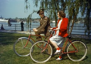 Siedząc na rowerach w pobliżu portu, oficer armii amerykańskiej flirtuje z młodą kobietą na Trini...
