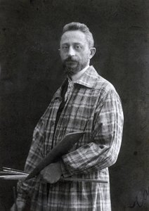 Portret malarza Guido Spadoliniego w ujęciu trzy czwarte długości. Malarz ubrany jest w długą pelerynę, w lewej ręce trzyma pędzle i paletę, 26111901