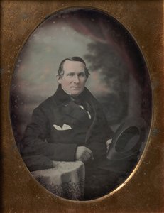 Mężczyzna w płaszczu i rękawiczkach, trzymający kapelusz, siedzący przed malowanym tłem, lata czterdzieste XIX wieku. autorstwa Samuel Broadbent Jr..