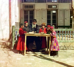 Grupa dzieci żydowskich z nauczycielem na stole przed domem, Samarkanda, Imperium Rosyjskie, w latach 1905-1915