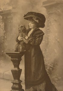 [Sarah Bernhardt stojąca w studiu, trzymająca małego czarnego pieska na ozdobnym, rzeźbionym drewnianym postumencie]. autorstwa Theodore C. Marceau