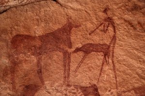 Sztuka naskalna, prehistoryczna: Malowidło naskalne przedstawiające krowę, cielę i postać (łucznika) w ozdobnym schronie w masywie Uweinat w Egipcie. (Okres od 8000 do 3000 lat pne). Fotografia autorstwa Unbekannt