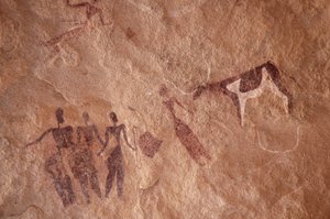 Sztuka naskalna, prehistoria: Malowidło naskalne przedstawiające grupę postaci i dwukolorową krowę z dużymi rogami w ozdobnym schronie, w masywie Uweinat w Egipcie. (Okres od 8000 do 3000 lat pne). Fotografia autorstwa Unbekannt