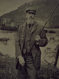 Portret studyjny ósmego księcia Devonshire w tweedach trzymającego wędkę przed wydrukowanym ekranem przedstawiającym Chatswortha autorstwa William M. Timlin