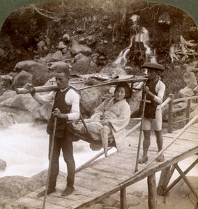 Japonka w górskim krześle yamakago przeprawiająca się przez rwącą rzekę Daiya w pobliżu Nikko w Japonii, autorstwa Underwood and Underwood