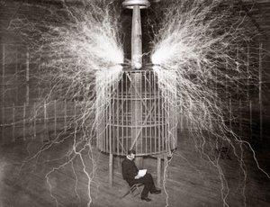 Nikola Tesla siedzący w swoim laboratorium w Colorado Springs ze swoim „nadajnikiem powiększającym” autorstwa Unknown photographer