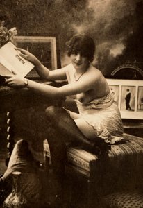 Portret młodej kobiety w intymnym stroju, siedzącej przy stole z książką. autorstwa Unknown photographer