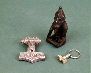 Amulety bóstw Wikingów: na pierwszym planie dwa małe srebrne młotki symbolizujące boga Thora. Statuetka przedstawia Freyra, boga płodności. Muzeum Historyczne w Sztokholmie, Szwecja.