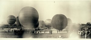Balony na ogrzane powietrze na polu w South St. Louis gotowe do startu; jeden jest już na niebie w oddali autorstwa W.C. Persons