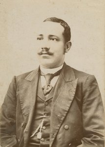 Zdjęcie mężczyzny w ciemnym garniturze z kieszonkowym zegarkiem w kamizelce, 1886-1900. autorstwa W. M. Hubbard