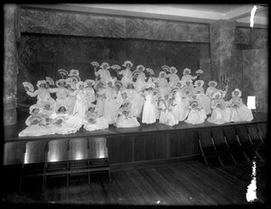 Grupa małych dziewczynek upozowanych na małej scenie trzymających wachlarze, prawdopodobnie w Roman Catholic Orphan Asylum, Kingsbridge, Bronx, ok. 1911 r. autorstwa William Davis Hassler