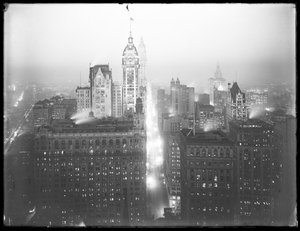 Zamglony nocny widok dolnego Manhattanu pod dużym kątem na północ, z widocznymi budynkami Singera, Woolwortha i Municipal Building, ok. 1913 r. autorstwa William Davis Hassler