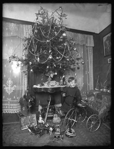 Chłopiec Seymour pozowany z trójkołowym rowerem obok choinki w salonie, Boże Narodzenie 1912