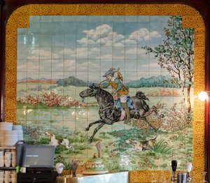 Widok wnętrza, panel kafelkowy, malarz Furcy Ernest Tondeur, egzekutor Boch Frères La Louvière, drugi panel przedstawia scenę polowania z galopującym jeźdźcem z rogiem myśliwskim autorstwa . .