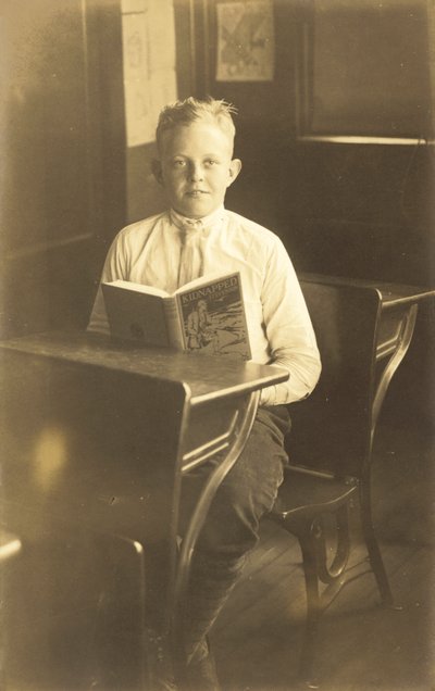 Chłopiec czytający Porwany (zdjęcie czarno-białe) autorstwa American Photographer