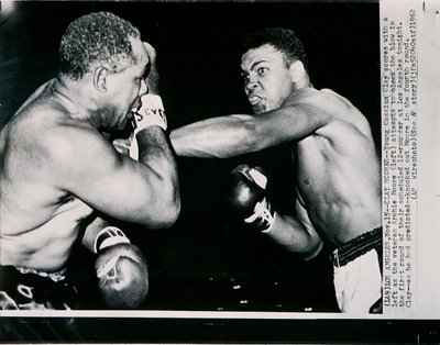 Młody Cassius Clay strzela lewą stroną przeciwko weteranowi Archie Moore w pierwszej rundzie walki w Los Angeles autorstwa American Photographer