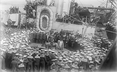 Marynarze tłoczą się wokół australijskiego premiera Hon Williama Morrisa (Billy) Hughesa, który przemawia do nich na pokładzie HMAS Australia w stoczni w Devon w Anglii, 21 maja 1916 r. autorstwa Australian Photographer