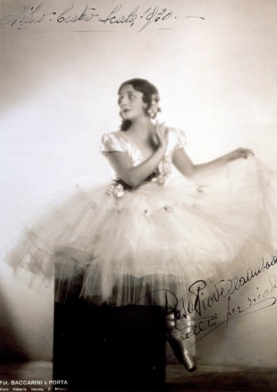 Portret klasycznej baletnicy Rosy Piovella Ansaldo, w tutu i baletkach. Siedzi z przodu, z twarzą zwróconą w bok. Róże z tkaniny zdobią jej ubranie i starannie ułożone włosy (Mediolan, Teatro alla Scala) (zdjęcie czarno-białe) autorstwa Baccarini and Porta