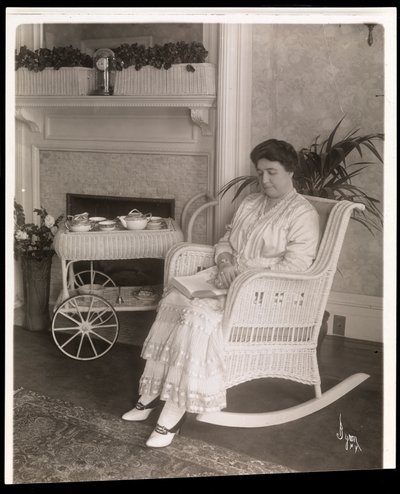 Pani Howard siedząca z książką na bujanym fotelu w swoim domu przy 200, 5th Avenue, Nowy Jork, 1915-6 (srebrny odbitka żelatynowa) autorstwa Byron Company
