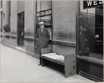 Niewidomy kioskarz, Frederick Rode, na południowo-wschodnim rogu Broadwayu i 41. ulicy. W oknie za panem Rode widać znak Western Union. autorstwa Company Byron