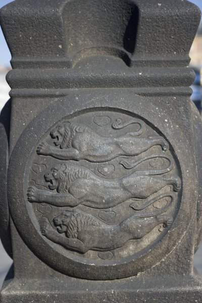 Symbol trzech lwów wyrzeźbiony w kamiennej kolumnie na Placu Ratuszowym autorstwa Danish School