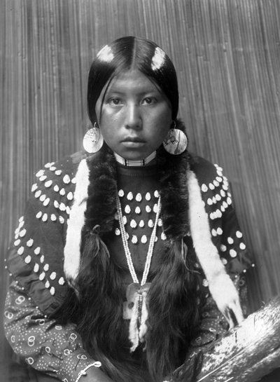 Kalispel Indianka, białe pasy namalowane na włosach, kolczyki w kształcie dysków muszli, ubrana w kocową suknię ozdobioną zębami łosia, ok. 1910, fot. Edward S. Curtis autorstwa Edward Sheriff Curtis