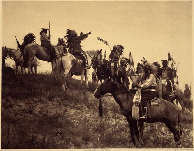 Planowanie nalotu. Indianie w swoich imponujących typowych strojach spotykają się w niezwykle malowniczych grupach. To oddział z Sioux Ogalala (Oglala), na wzgórzu z widokiem na dolinę Wounded Knee w rezerwacie Pine Ridge w Południowej Dakocie. zdjęcie autorstwa Edward Sheriff Curtis