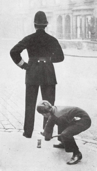 Chłopiec robiący psikusa policjantowi (zdjęcie czarno-białe) autorstwa English Photographer