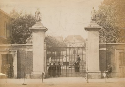Dzieci stoją patrząc przez bramę szkoły autorstwa English Photographer