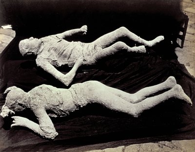 Dwa odlewy postaci ludzkich z wykopalisk w Pompejach. Eksponaty zostały umieszczone na czarnym materiale w celu ich sfotografowania autorstwa Giorgio Sommer