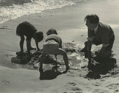 Trójka dzieci bawiących się piaskiem na plaży. autorstwa Godfrey Macdominic